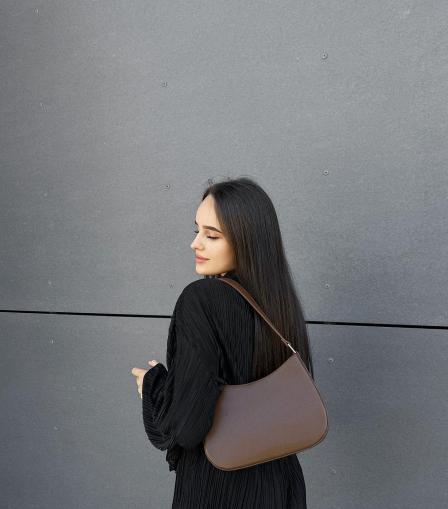 A-person-wearing-a-black,-longSleeved-outfit-and-carrying-a-beige-Alicia-Small-shoulder-bag.jpg